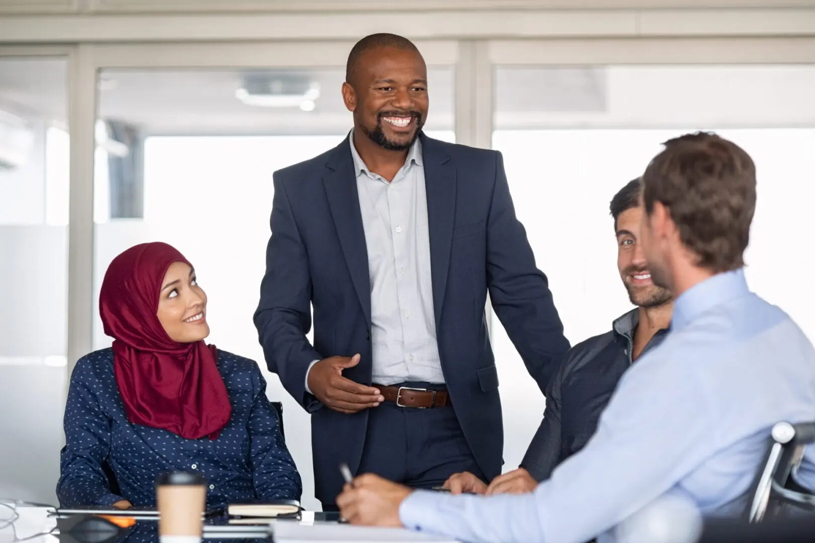 Entrepreneurs, partners and islamic woman conference in modern meeting room. Happy mature african businessman putting forward his suggestions to colleagues. Group of multiethnic business people brainstorming together.